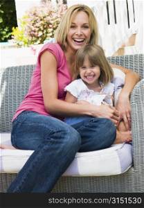 Woman and young girl sitting on patio laughing