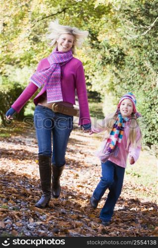 Woman and young girl walking on path outdoors smiling (selective focus)