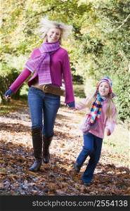 Woman and young girl walking on path outdoors smiling (selective focus)