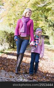 Woman and young girl walking outdoors in park and smiling