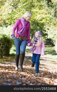 Woman and young girl walking outdoors in park and smiling