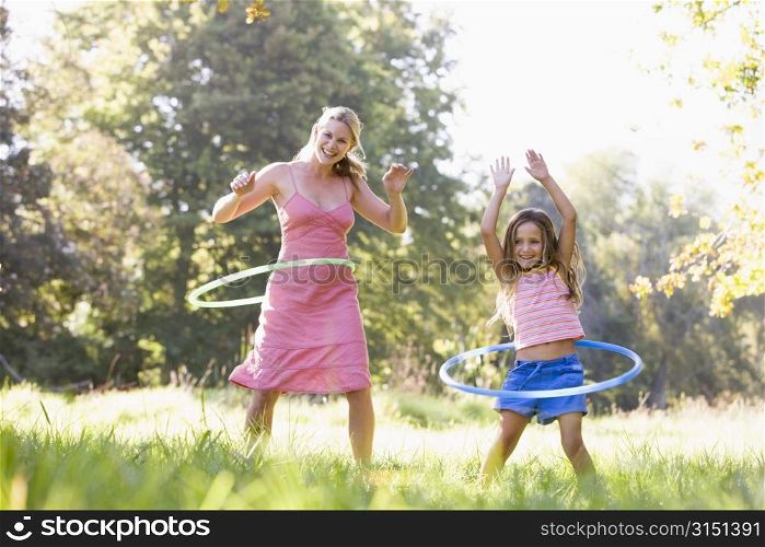 Woman and young girl with hula hoops outdoors smiling