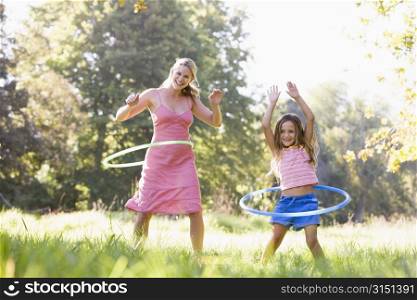 Woman and young girl with hula hoops outdoors smiling