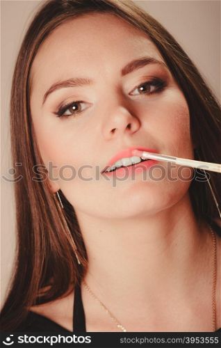 Woman aplying lip gloss. Beauty of women. Cosmetics and make up idea. Portrait of young attractive woman model aplying pink lip gloss lipstick.
