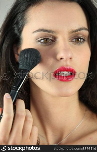 Woman applying blush on her cheeks