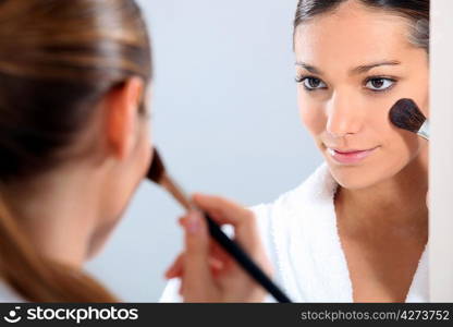 Woman applying blusher in a mirror