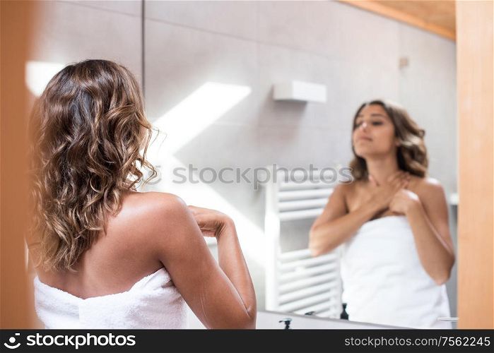 Woman applying body cream after bath