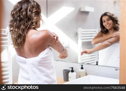 Woman applying body cream after bath