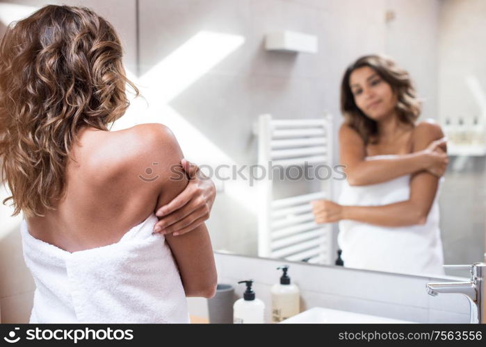 Woman applying body cream after bath