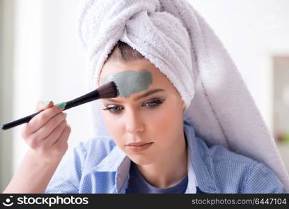 Woman applying clay mask with brush at home