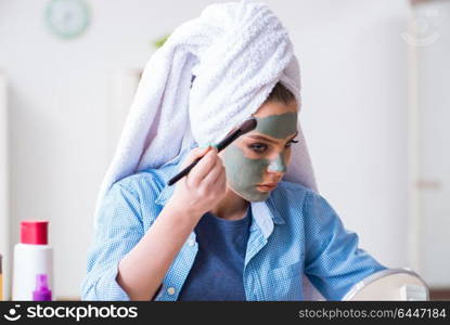 Woman applying clay mask with brush at home