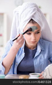 Woman applying clay mask with brush at home