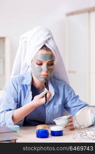 Woman applying clay mask with brush at home