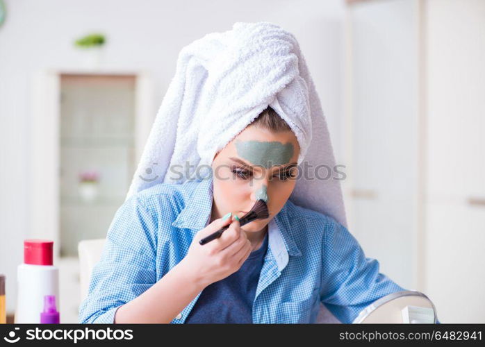 Woman applying clay mask with brush at home