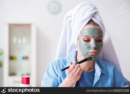 Woman applying clay mask with brush at home