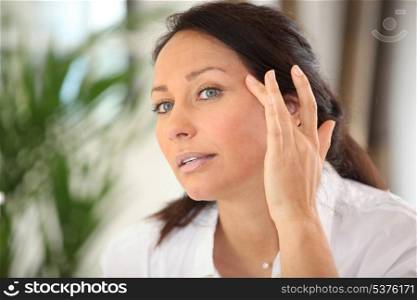 Woman applying cream on her face
