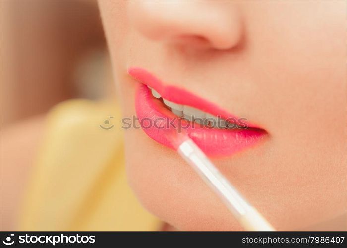 Woman applying lipstick with brush on lips. Makeup. Close up of woman applying lipstick with brush on lips. Girl beautifying herself. Beauty and make up concept.