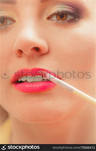 Woman applying lipstick with brush on lips. Makeup. Close up of woman applying lipstick with brush on lips. Girl beautifying herself. Beauty and make up concept.