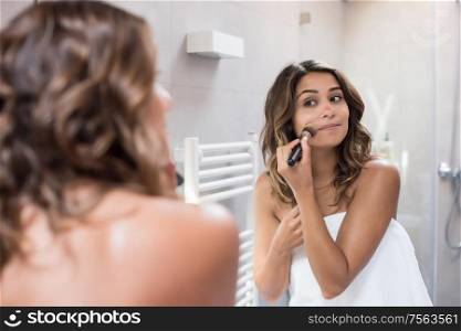 Woman applying make up in the bathroom