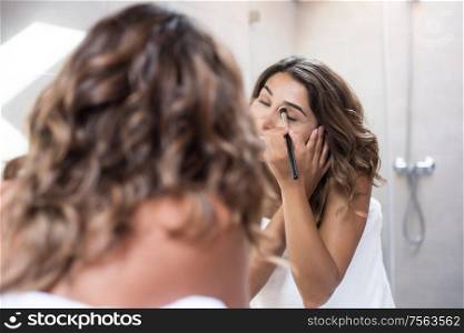 Woman applying make up in the bathroom
