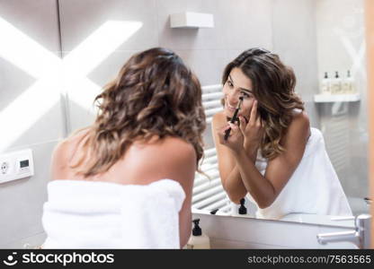 Woman applying make up in the bathroom