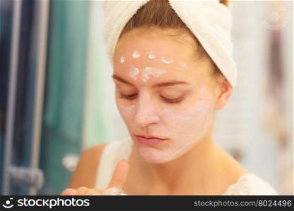 Woman applying mask cream on face in bathroom. Woman applying mask moisturizing skin cream on face in bathroom. Girl taking care of her complexion layering moisturizer. Skincare spa treatment.