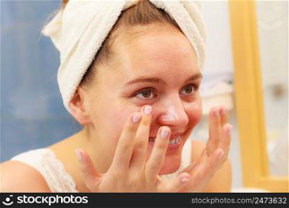 Woman applying mask moisturizing skin cream on face in bathroom. Girl taking care of her complexion layering moisturizer. Skincare spa treatment. . Woman applying mask cream on face in bathroom