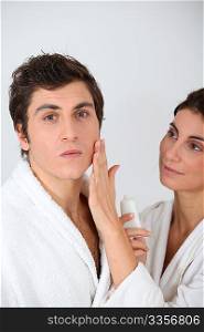 Woman applying moisturizer on boyfriend&acute;s cheek