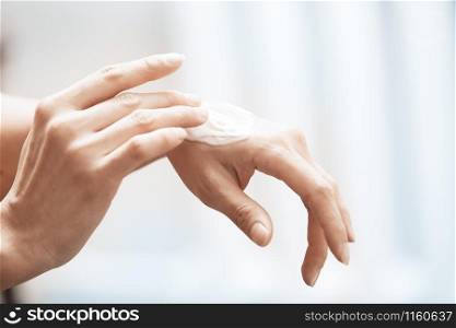 Woman applying moisturizing cream on hands