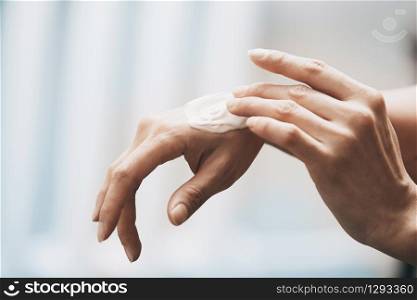 Woman applying moisturizing cream on hands
