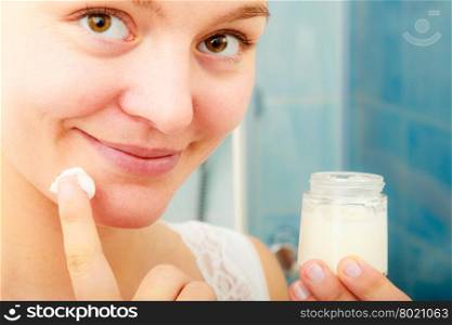 Woman applying moisturizing skin cream. Skincare.. Young woman applying cleansing moisturizing skin cream on face. Girl taking care of dry complexion layering moisturizer. Skincare.