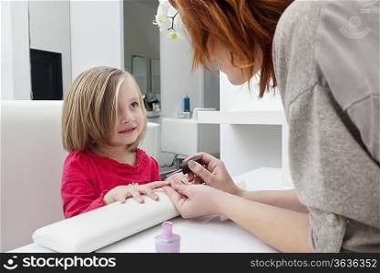Woman applying nail polish on little girl&acute;s hand