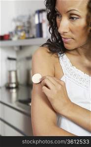 Woman applying patch to arm, indoors, close-up