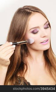 Woman applying rouge with brush to her face. Woman applying rouge with brush to her face. Pretty gorgeous girl beautifying. Fashion and makeup