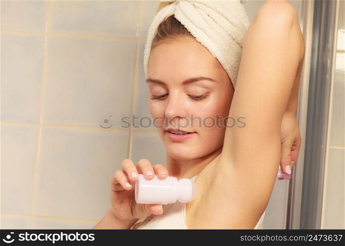 Woman applying stick deodorant in armpit. Girl putting antiperspirant in underarms in bathroom. Daily skin care and hygiene.. Woman applying stick deodorant in armpit