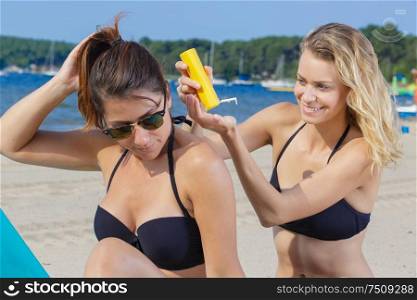 woman applying suncream to her friends back