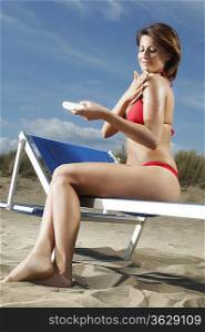 Woman Applying Sunscreen on Beach