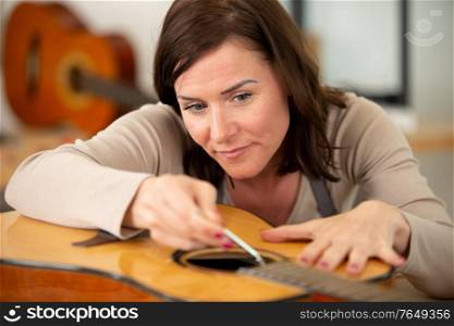 woman as trainee fixing guitar