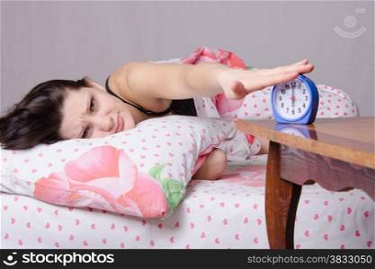 Woman asleep in bed, standing beside an alarm clock on the table, the places on the six o&#39;clock