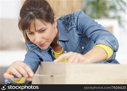 woman assembling furniture at home on the floor
