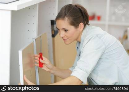woman assembling furniture with screwdriver