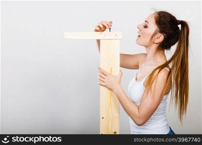 Woman assembling wooden furniture. DIY.. Woman assembling wooden furniture using hex key. DIY enthusiast. Young girl doing home improvement.