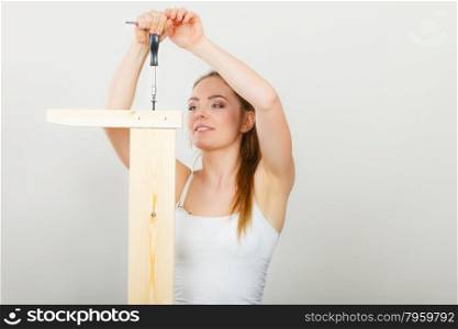 Woman assembling wooden furniture. DIY.. Woman assembling wooden furniture using screwdriver. DIY enthusiast. Young girl doing home improvement.