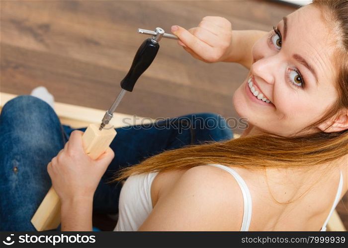 Woman assembling wooden furniture. DIY.. Woman assembling wooden furniture using screwdriver. DIY enthusiast. Young girl doing home improvement.