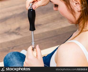 Woman assembling wooden furniture using screwdriver. DIY enthusiast. Young girl doing home improvement.. Woman assembling wooden furniture. DIY.