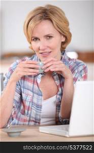 Woman at a laptop computer drinking a cup of coffee