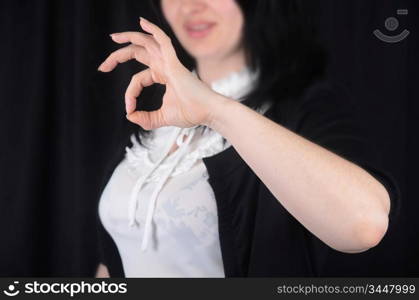 Woman at background indicating ok sign on a black background