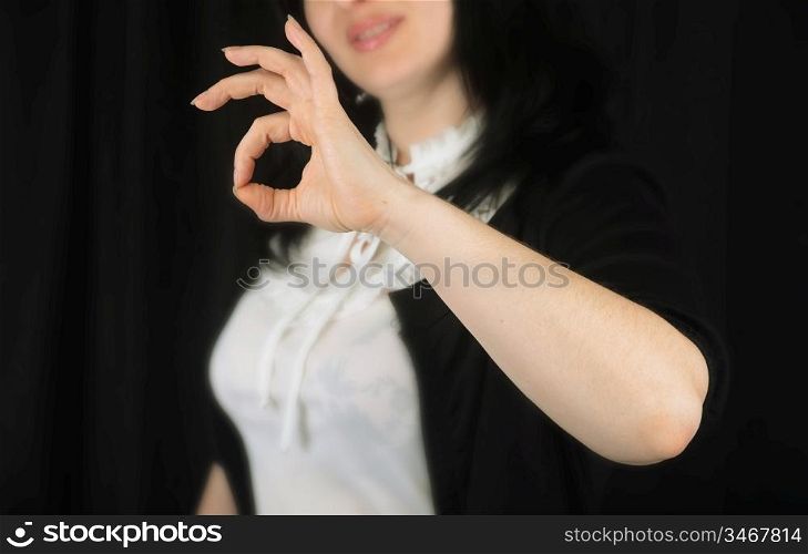 Woman at background indicating ok sign on a black background