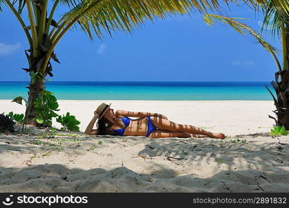 Woman at beach under palm tree with leaf shadow on her body