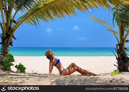 Woman at beach under palm tree with leaf shadow on her body